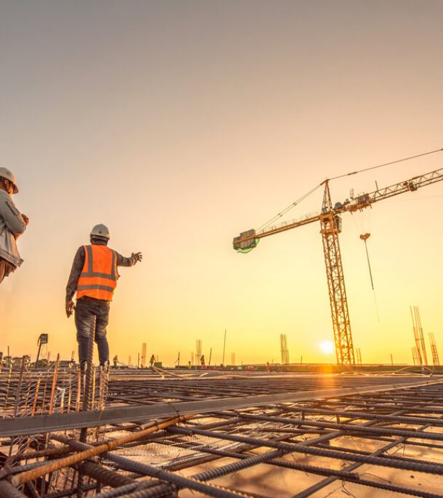 silhouette group of worker and civil engineer  in safety uniform install reinforced steel column in construction site during sunset time industrial concept